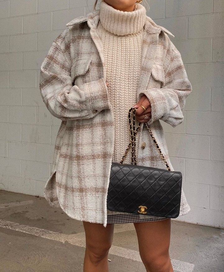 woman wearing oversized sweater turtleneck and plaid shacket over it. Woman is wearing a black channel purse