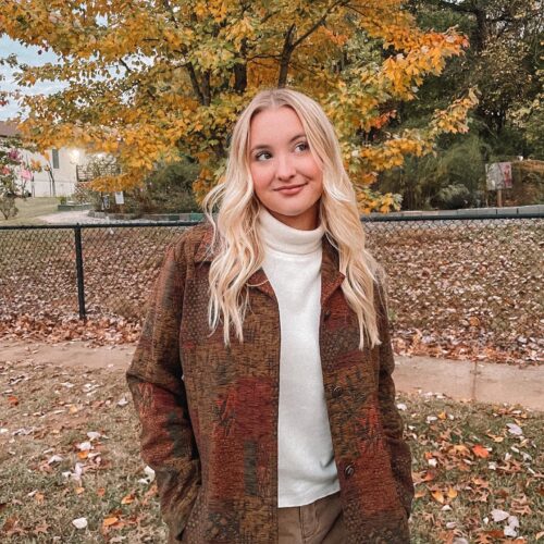 Blonde Influencer in Thrifted Patch-work Coat in the Fall under a tree with a turtleneck on